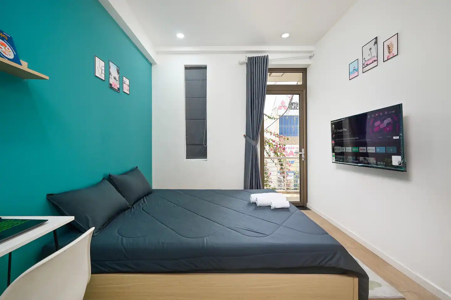 Studio R2.1 interior with queen bed, work desk and balcony door